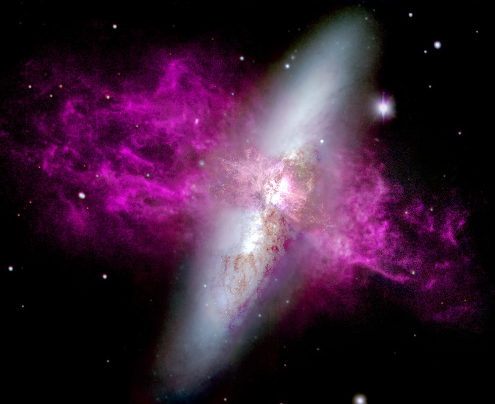 The 12-foot circular mosaic depicts massive jets of hot hydrogen gas (pink regions) being expelled from M82 as a result of an explosive burst of star formation in the center of the galaxy.