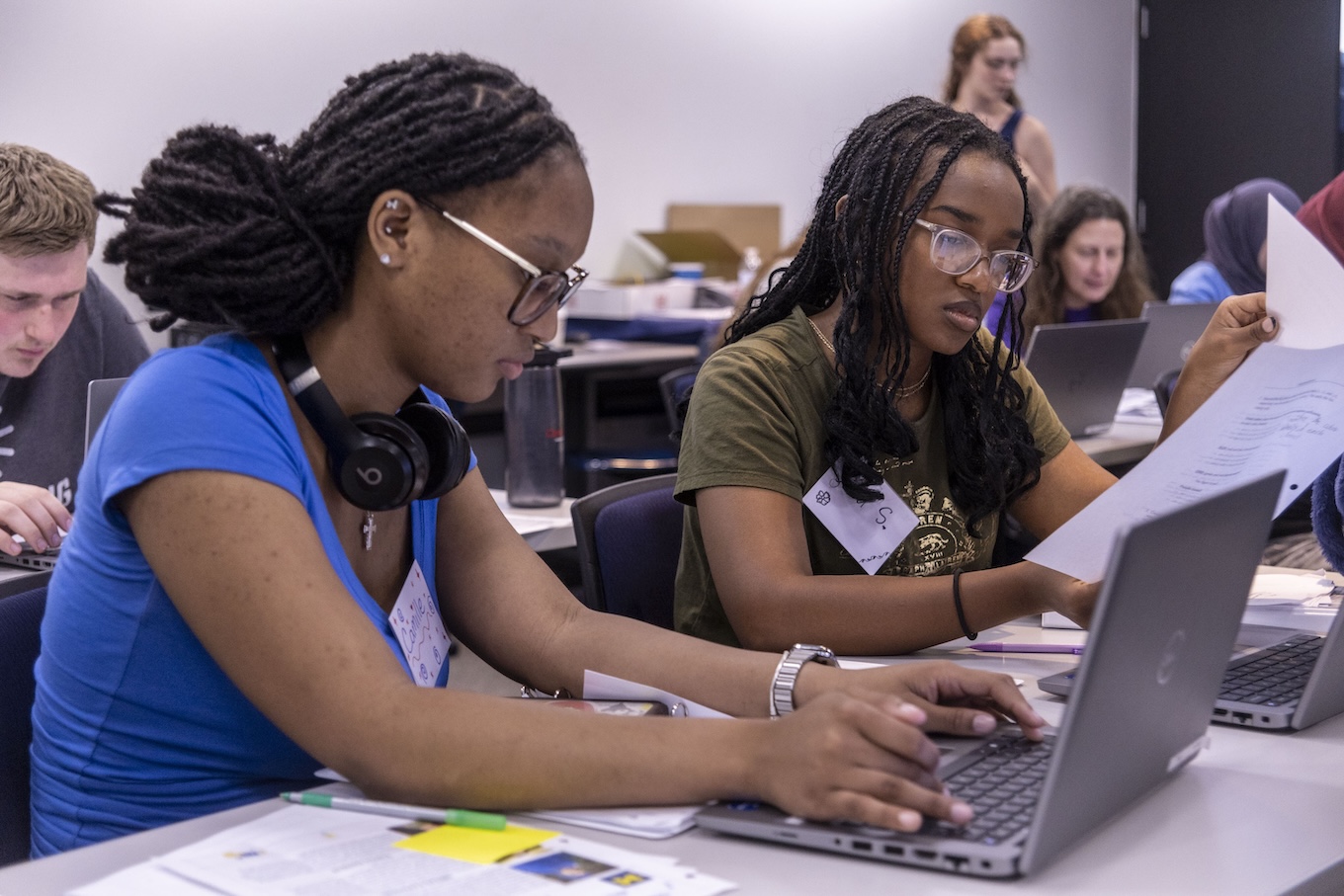 Two female high school students study math on their laptops.