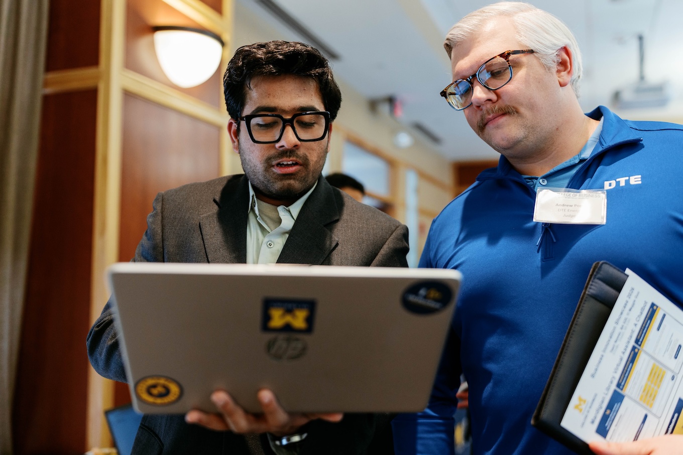 Two men review a research project in front of a laptop.