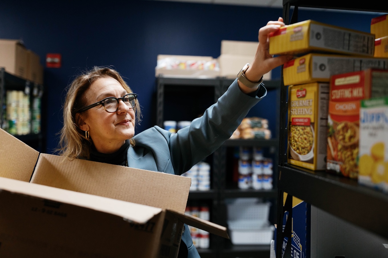 A woman puts a food item on a shelf.