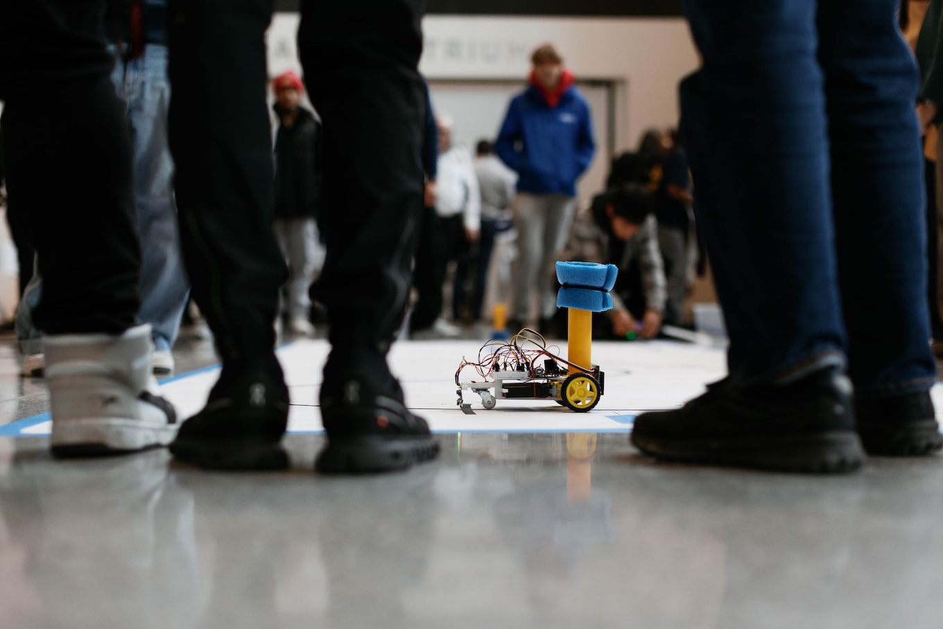 A small robotic maize and blue car is on the ground and ready to race.