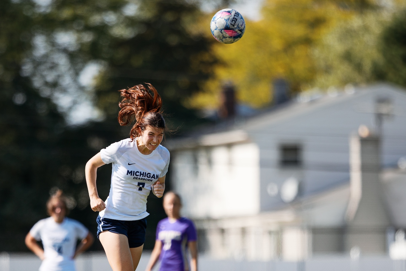 A woman jumps in the air to use her head to bump the soccer ball