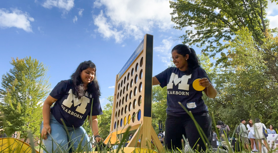 Two students play a giant connect four game on the UM-Dearborn campus on a summer day