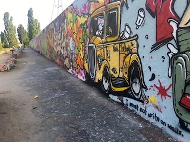 Assistant Professor Kristin Poling studies border walls and how societies relate to them. Here's a photo she took of Berlin's Mauerpark, where a strip of the Berlin Wall stands as a monument. It's also where graffiti artists can display their talent.