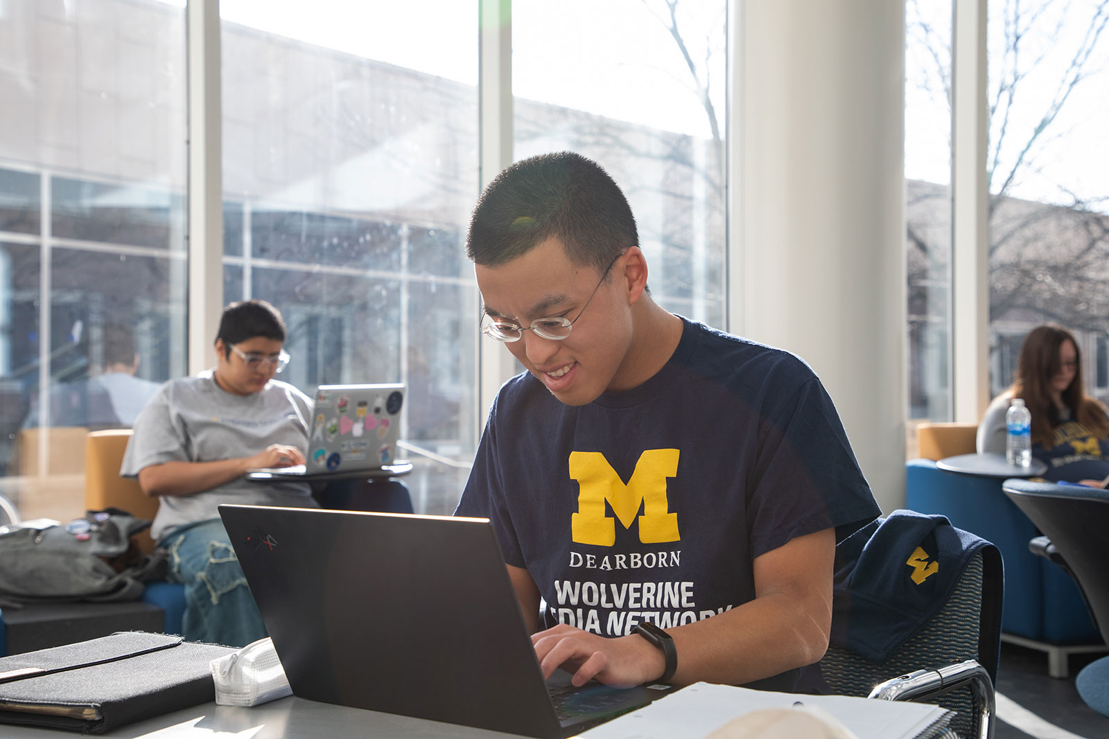 Student works on computer in CASL building atrium