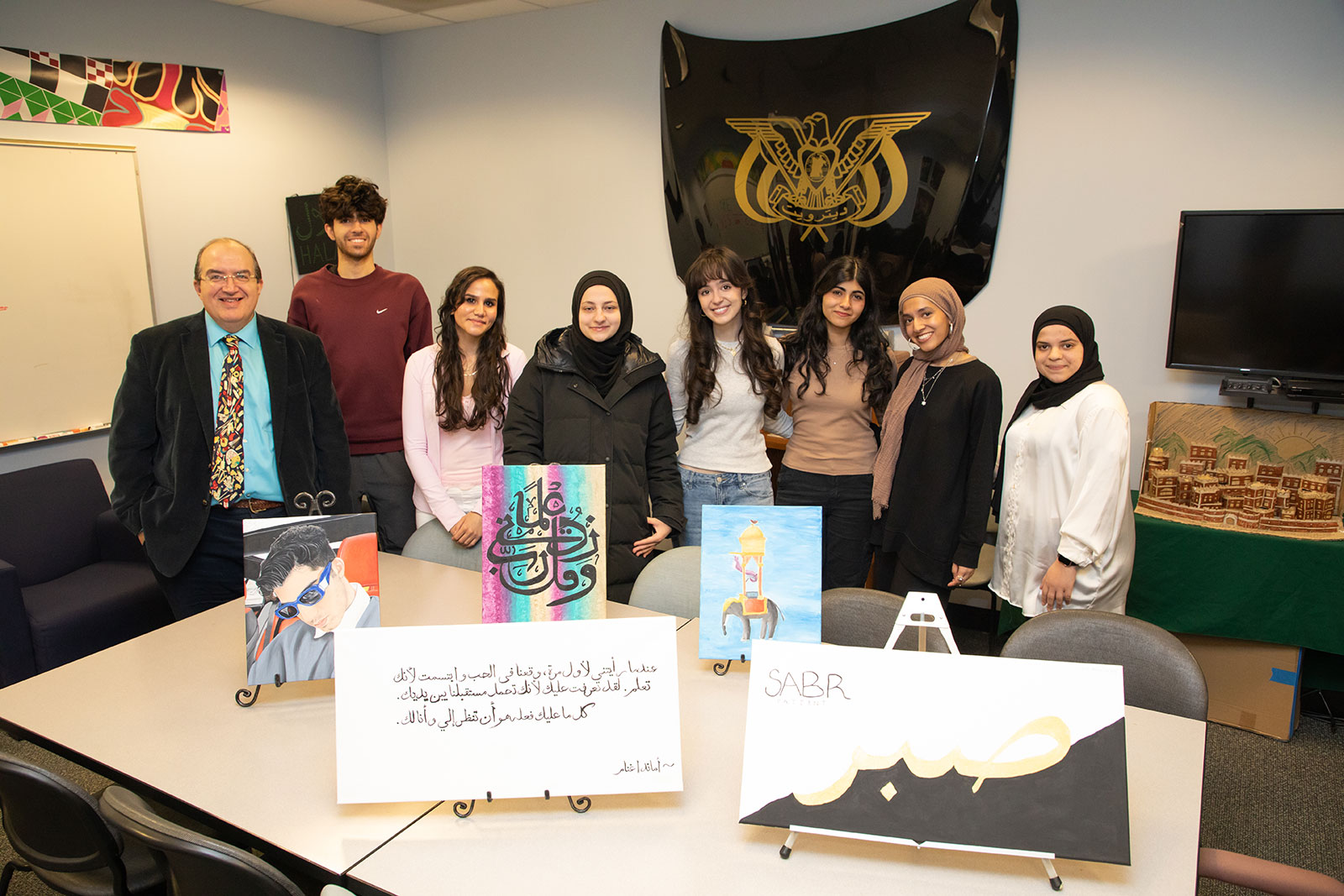 Students and professor pose with Arabic Art work 