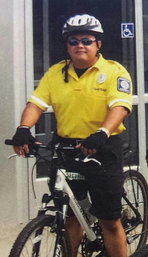 A man wearing yellow is seated on a bike with a white helmet.