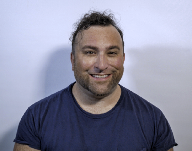 headshot of man smiling in front of white backdrop