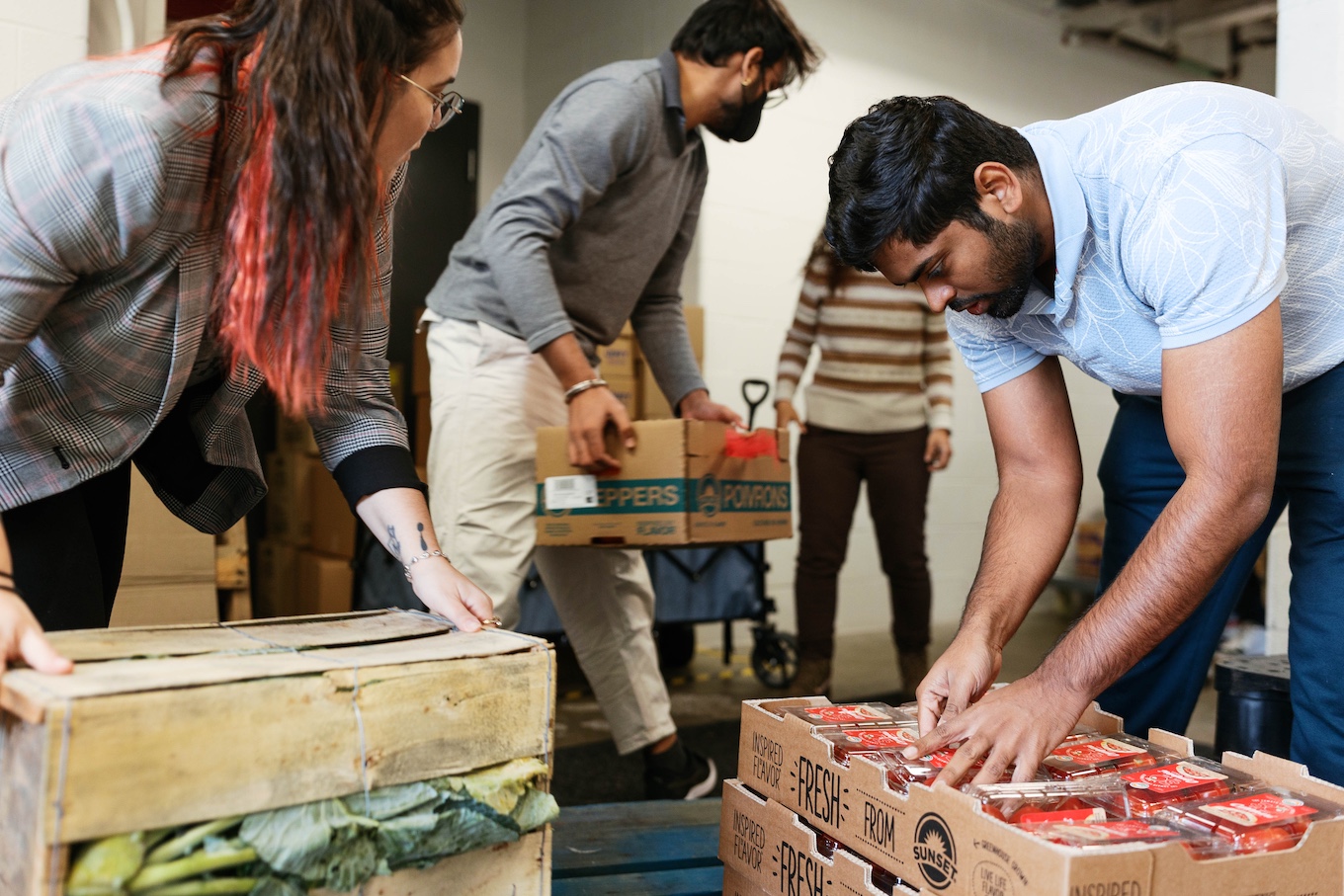 A group of people unpack boxes of food in the food pantry.