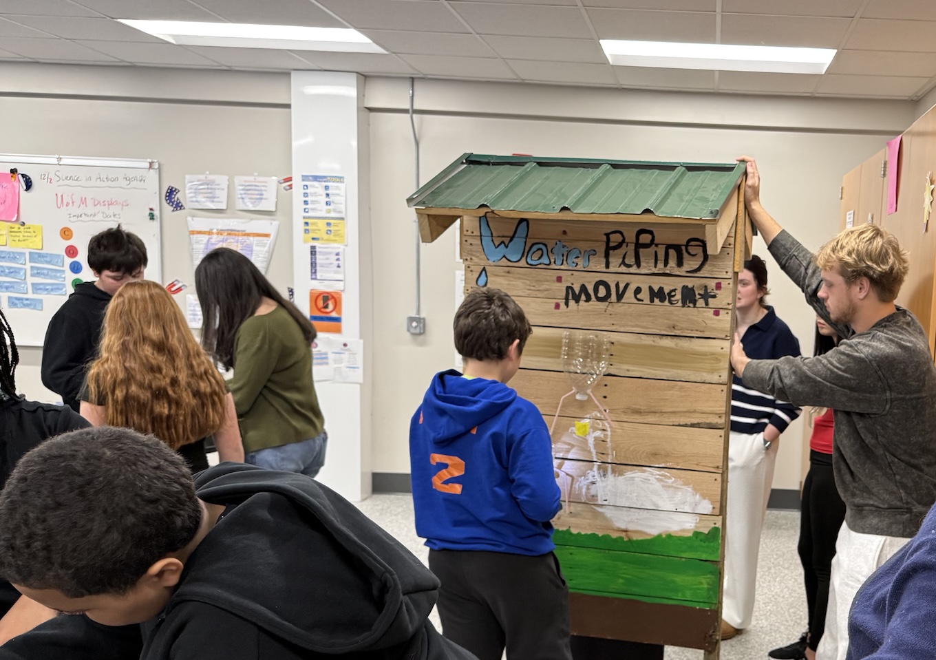 Middle school students work on science projects, including understanding water piping and flow.
