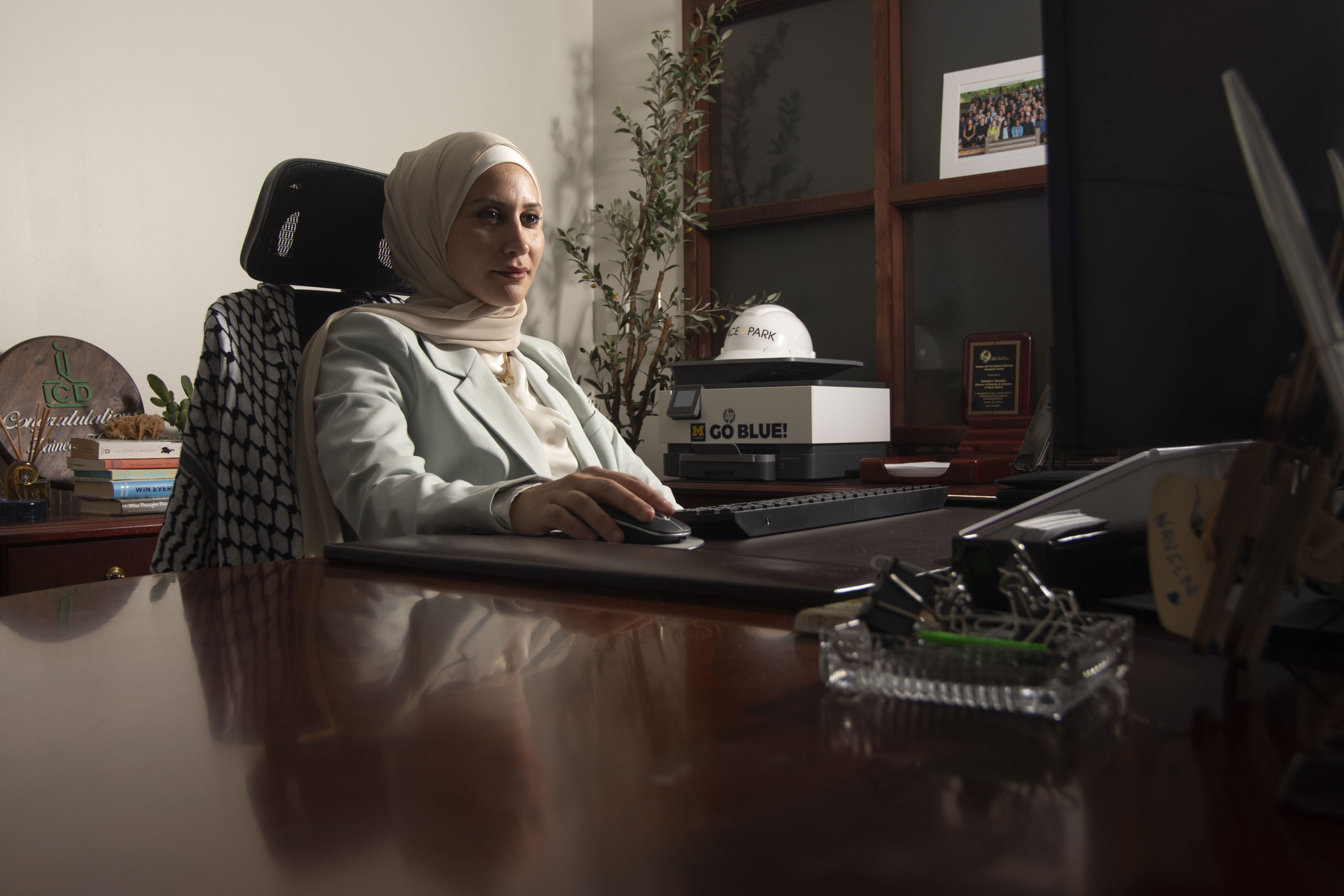 Seated at a desk in her office, Zaineb Hussein looks at a computer screen in her office.