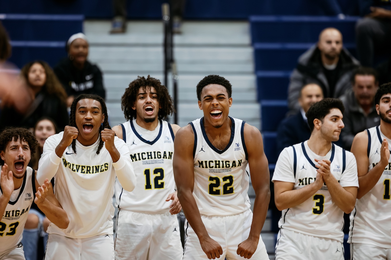 A group of male basketball players cheer for their team.