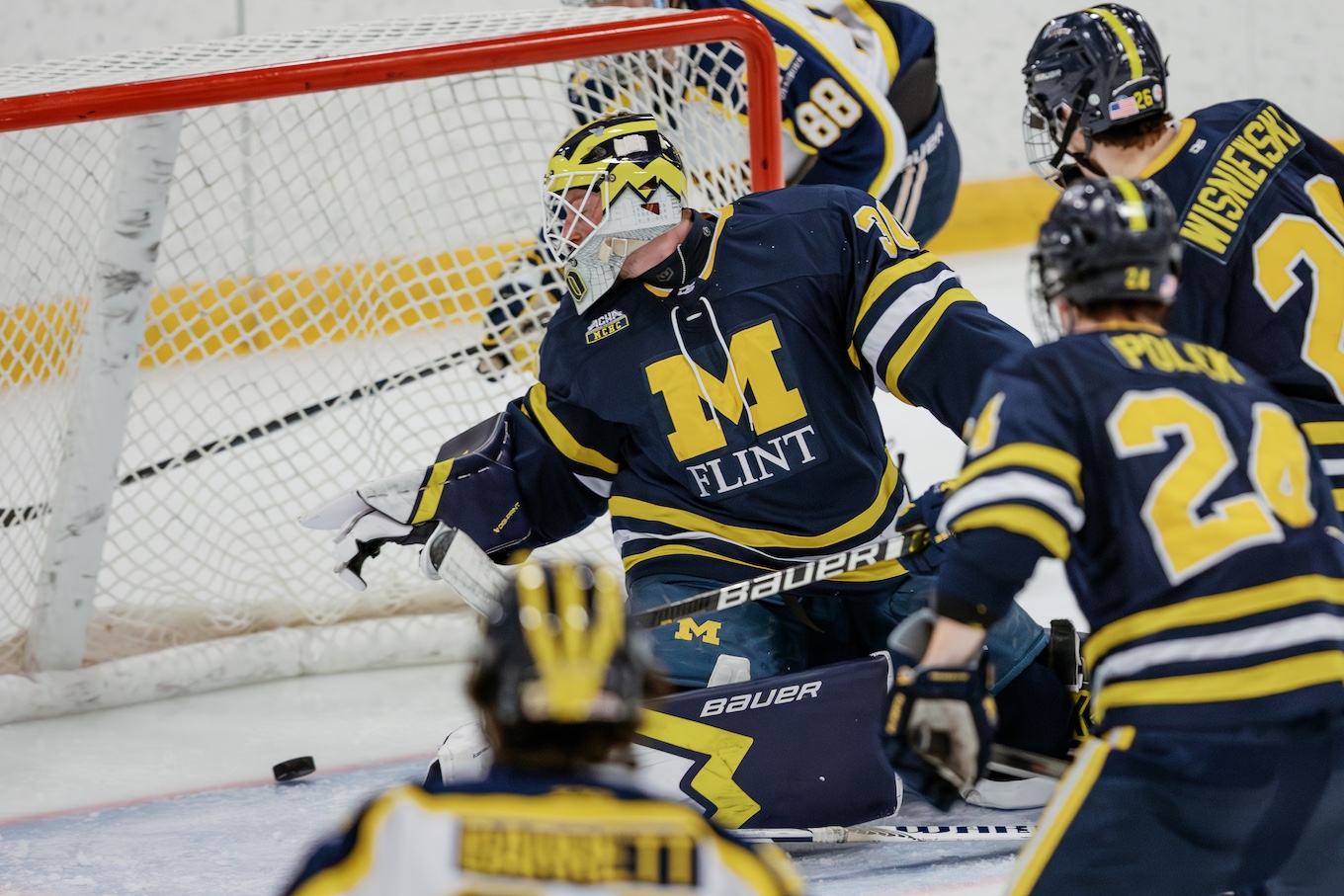 A hockey goalie for UM-Flint watches the puck go into the net.
