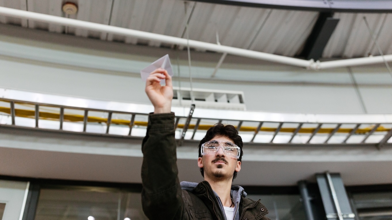 A male flies a paper airplane as a part of Engineering Week.