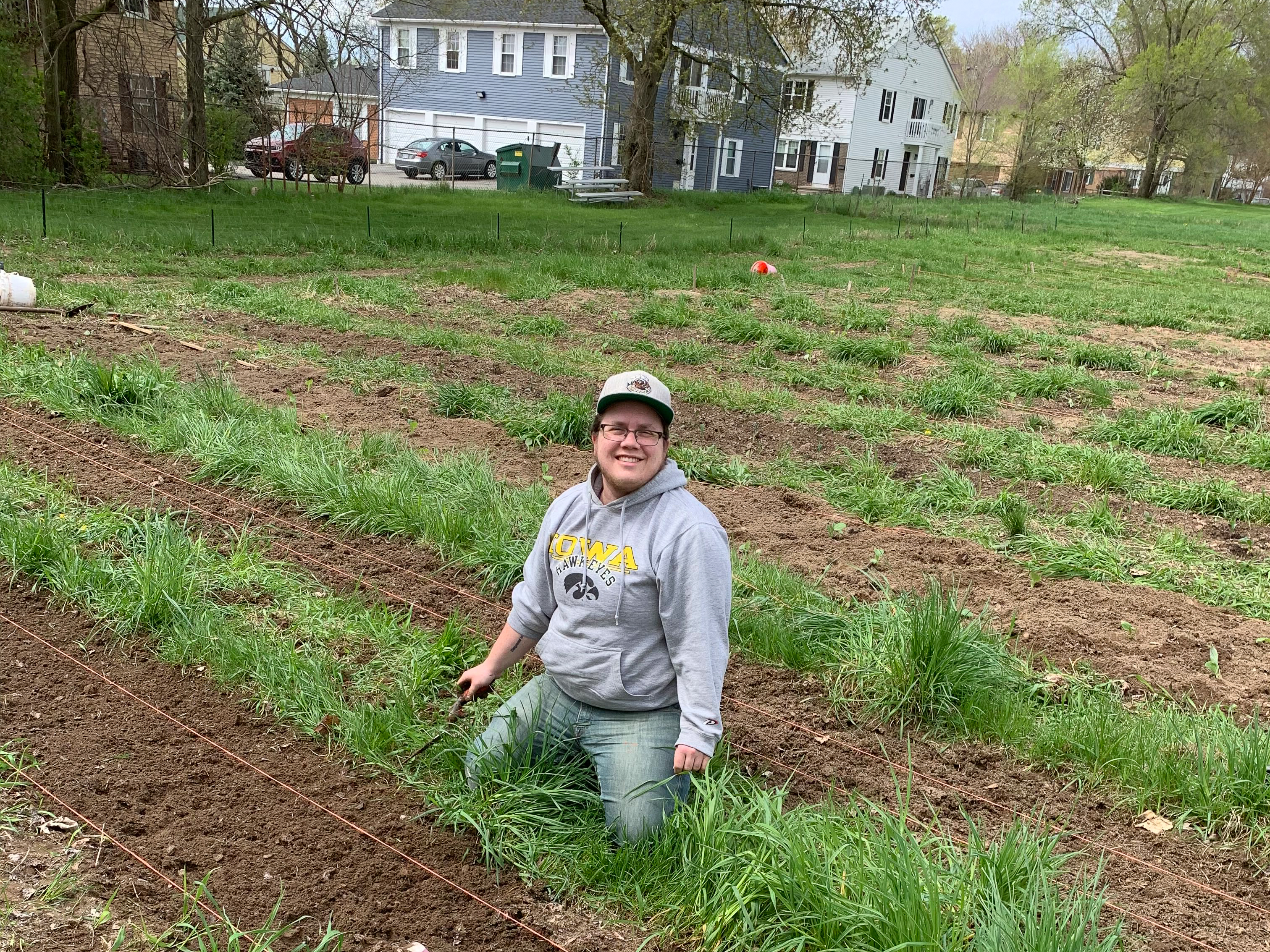 Finn Bell crouched down on the ground preparing soil for planting on a cloudy spring day