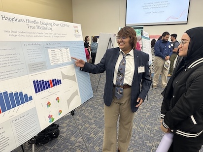 Student Researcher pointing to poster