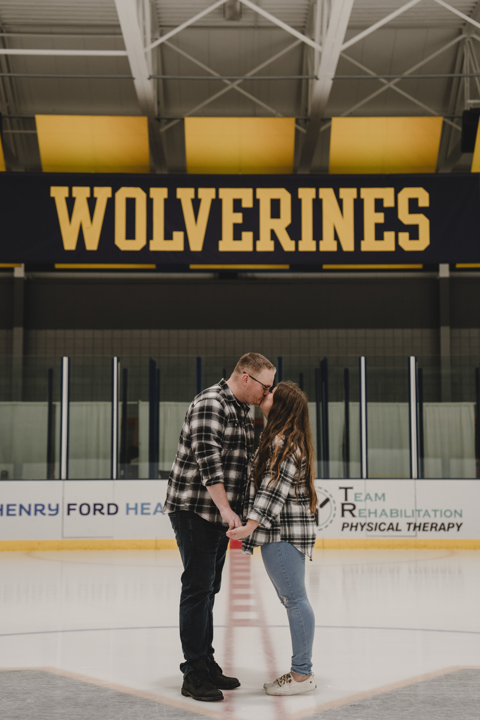 Allyssa Kerby and Nick McCutcheon kiss at center ice of a hockey area
