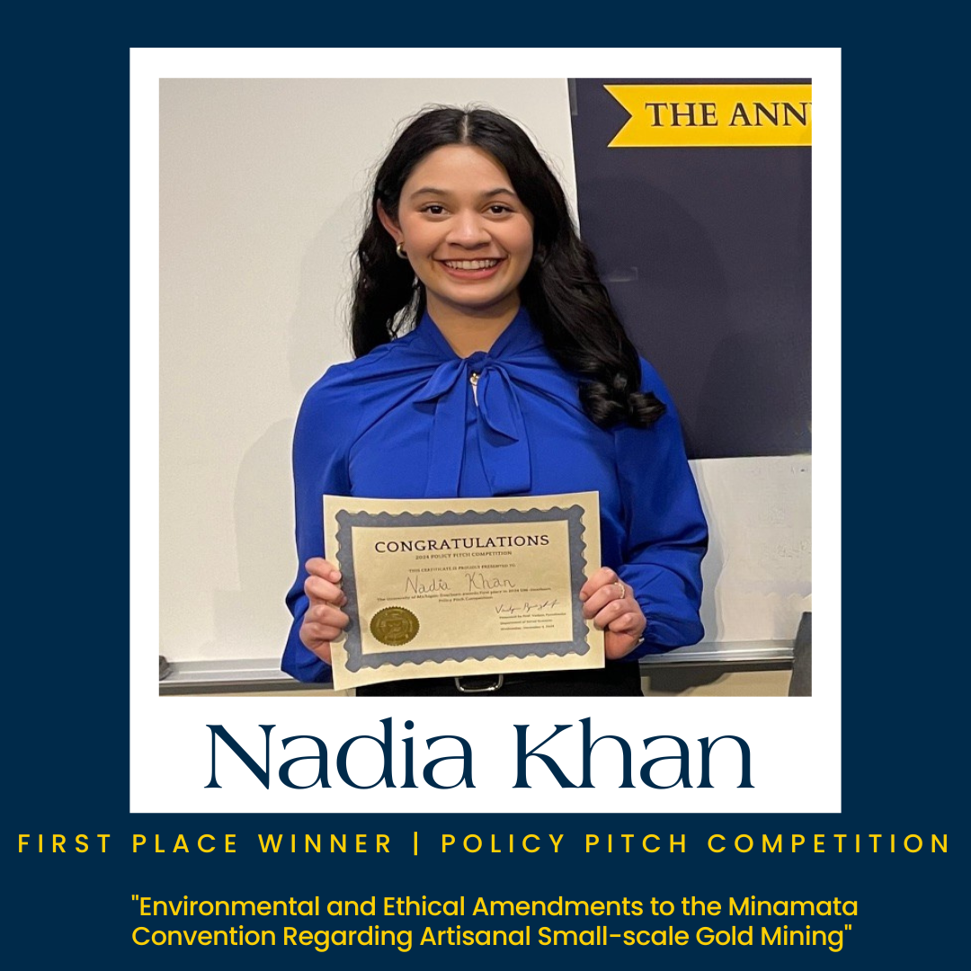 Policy Pitch Winner stands with award, smiling in blue shirt with text that says “first place winner, policy pitch competition”