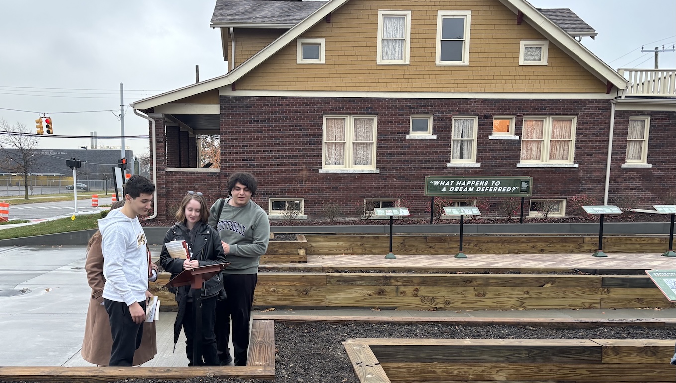 Three students stand outside the red-brick historic Ossian House and explore the park next to it.