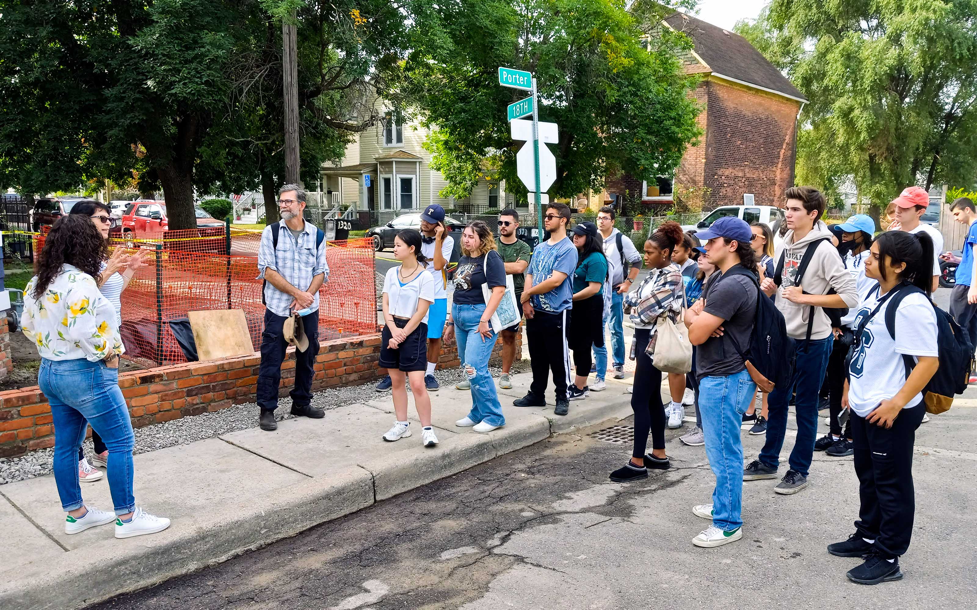 A class of UM-Dearborn students gather on a sidewalk in a Southwest Detroit neighborhood and listen to a local business owner. 