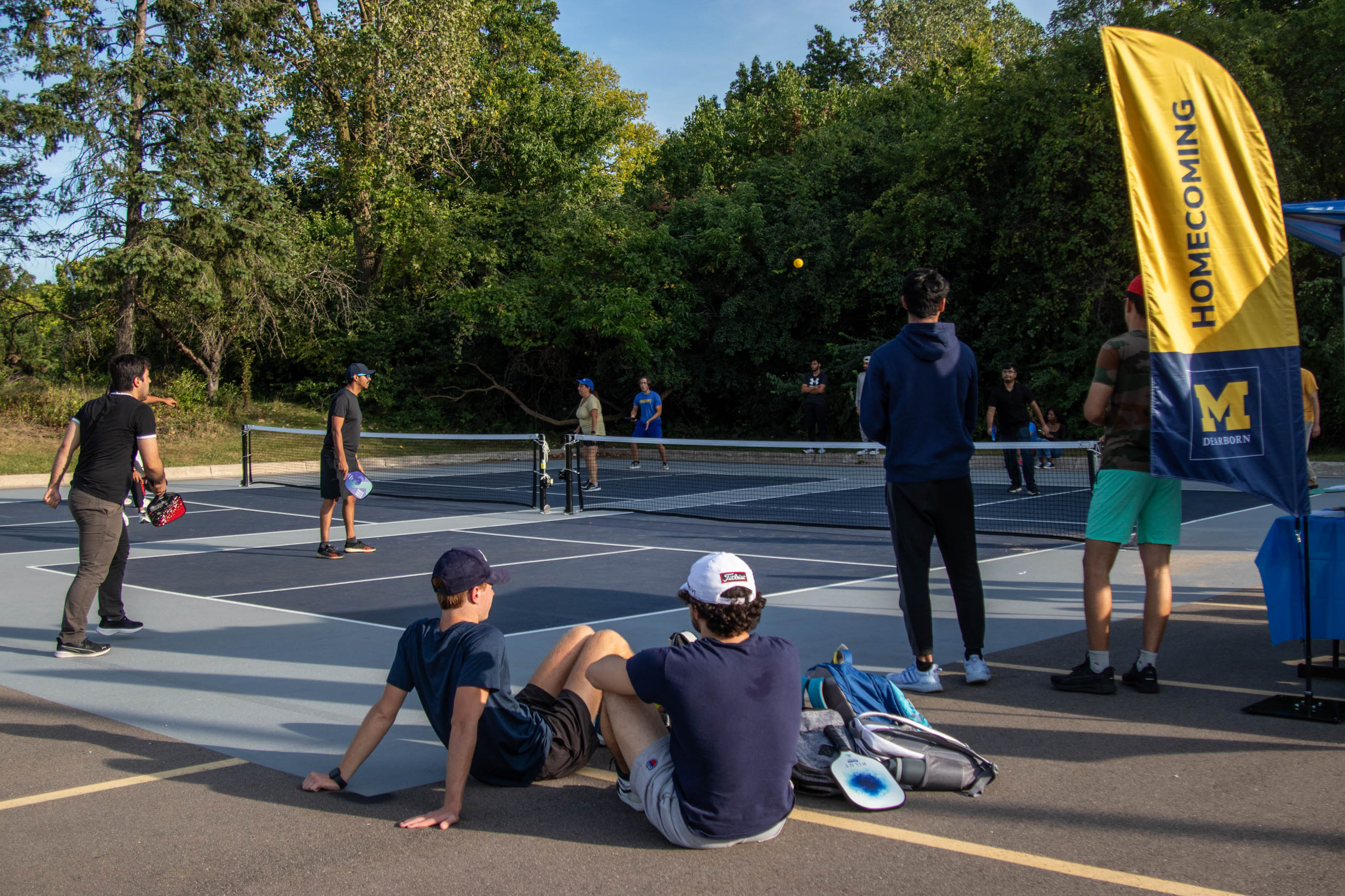 Students sit and watch people playing pickleball