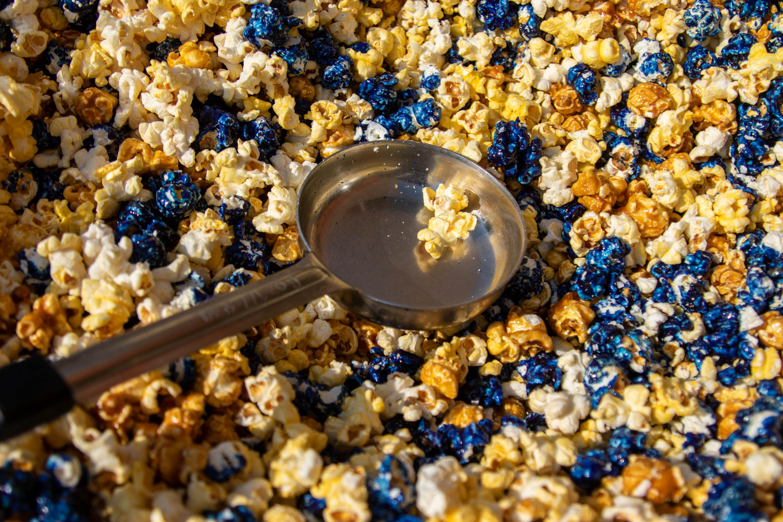 A closeup of yellow and blue popcorn with a frying pan