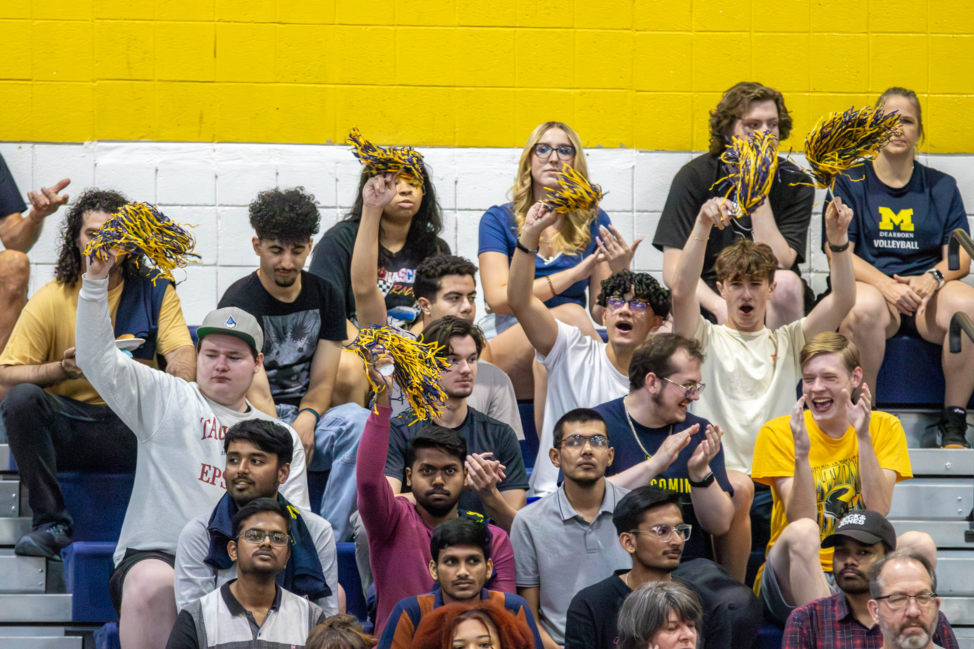 Students sit in the stands waving pompons at an athletics event