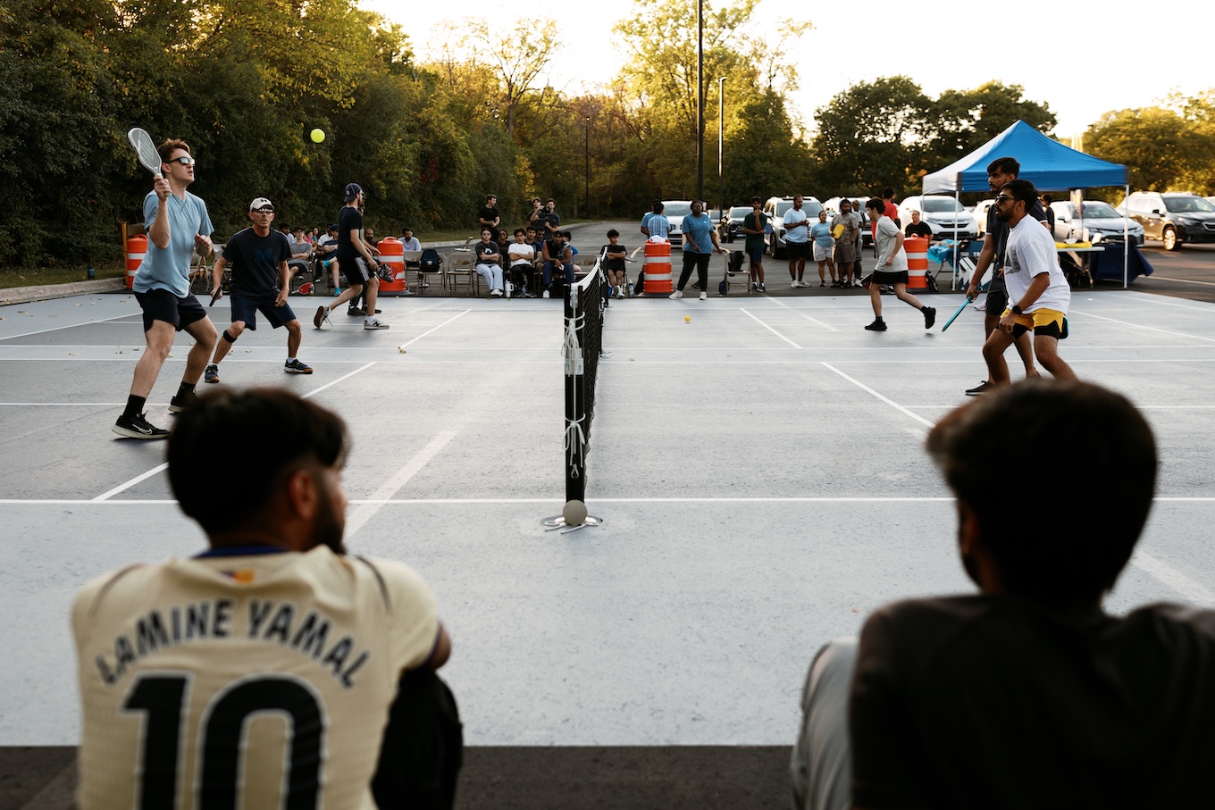 Four students hit a yellow ball across the net with racquets. 
