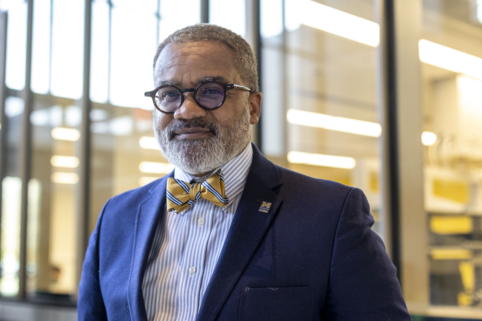 Wearing a blue blazer and a maize-and-blue bow tie, Education Lecturer Rashid Faisal stands for a portrait on the UM-Dearborn campus.