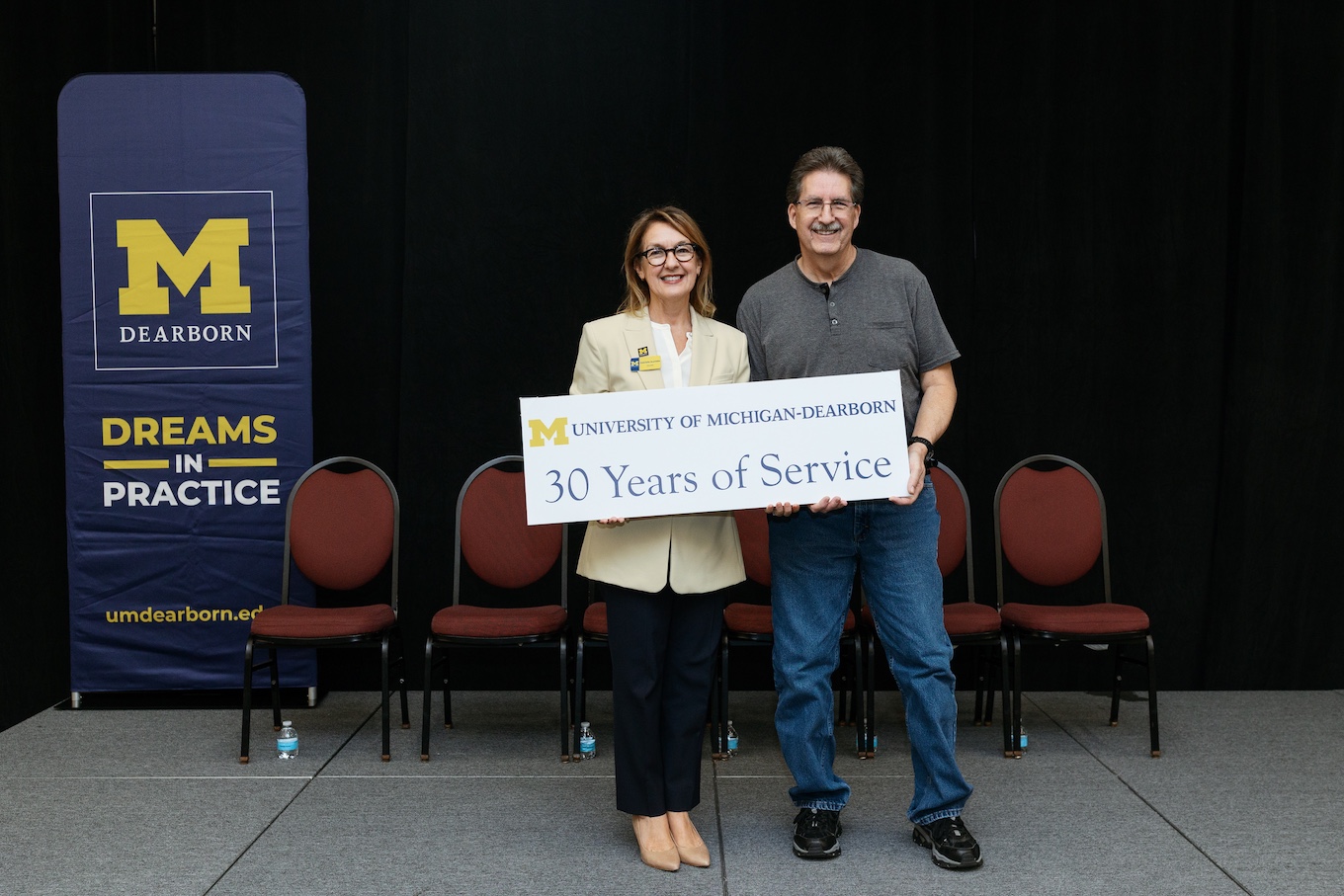 Well-dressed staff members stand together with a sign that reads "30 Years of Service"