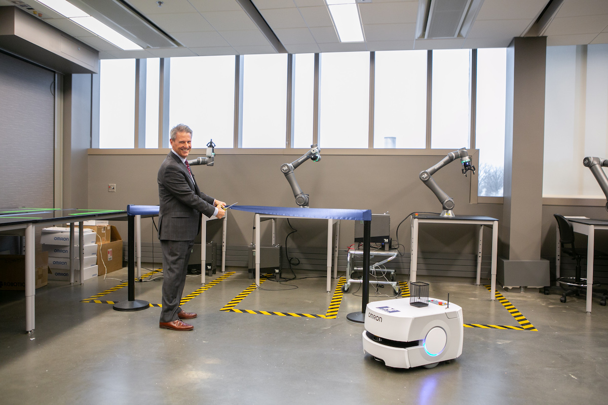 A mobile robot delivers scissors to Omron's Robb Black for a ceremonial ribbon cutting in the new lab.