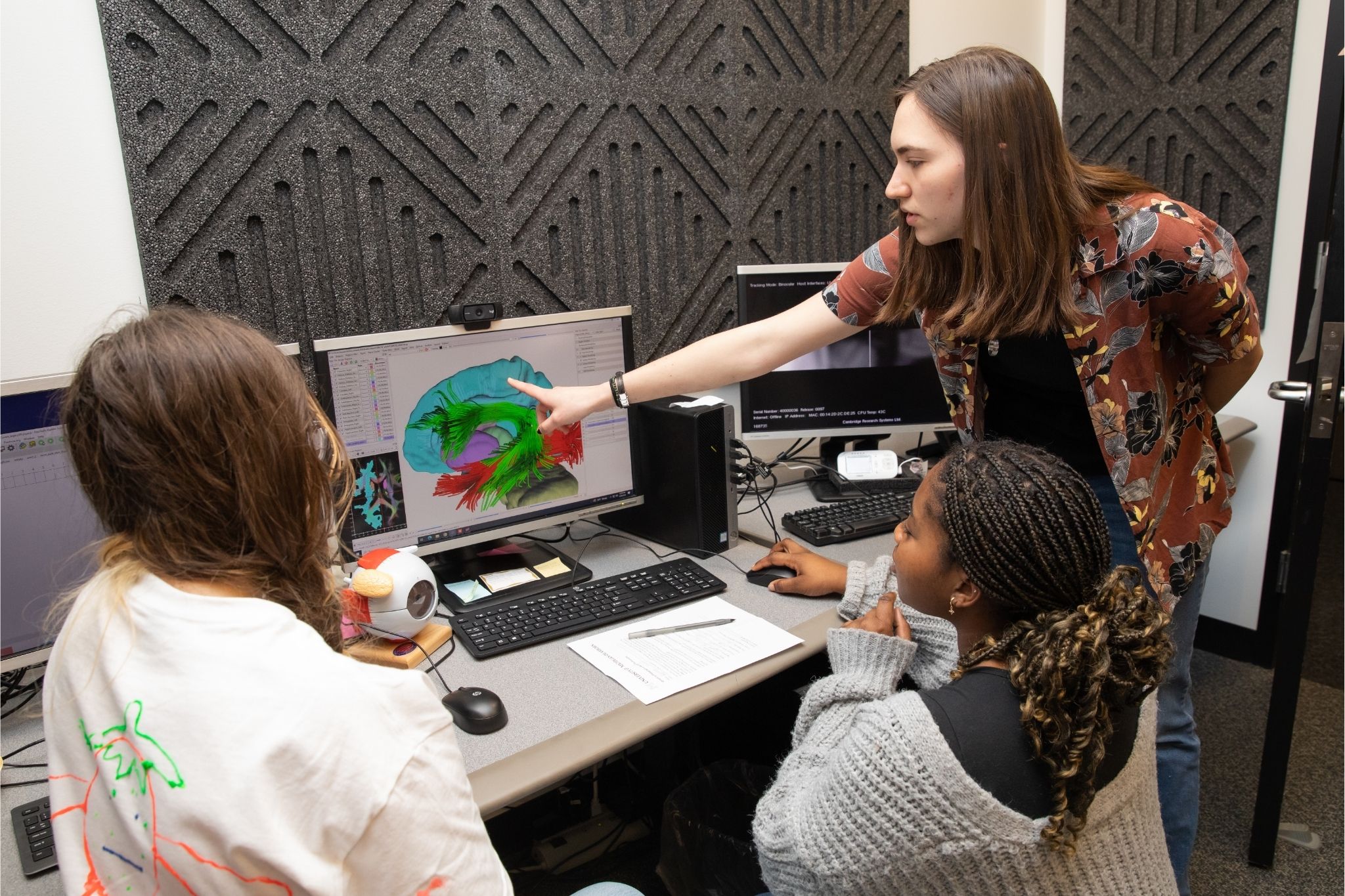 Three students analyze a computer screen that shows brain activity in psych class.