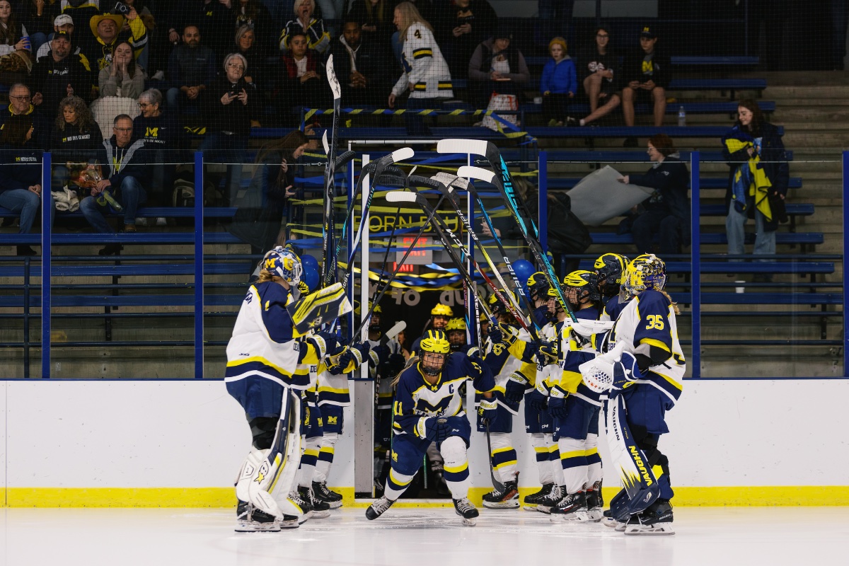 University of Michigan-Dearborn Women’s Hockey players form a tunnel with raised sticks as a teammate skates onto the ice before a game.