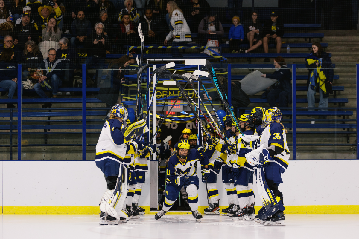 University of Michigan-Dearborn Women’s Hockey players form a tunnel with raised sticks as a teammate skates onto the ice before a game.