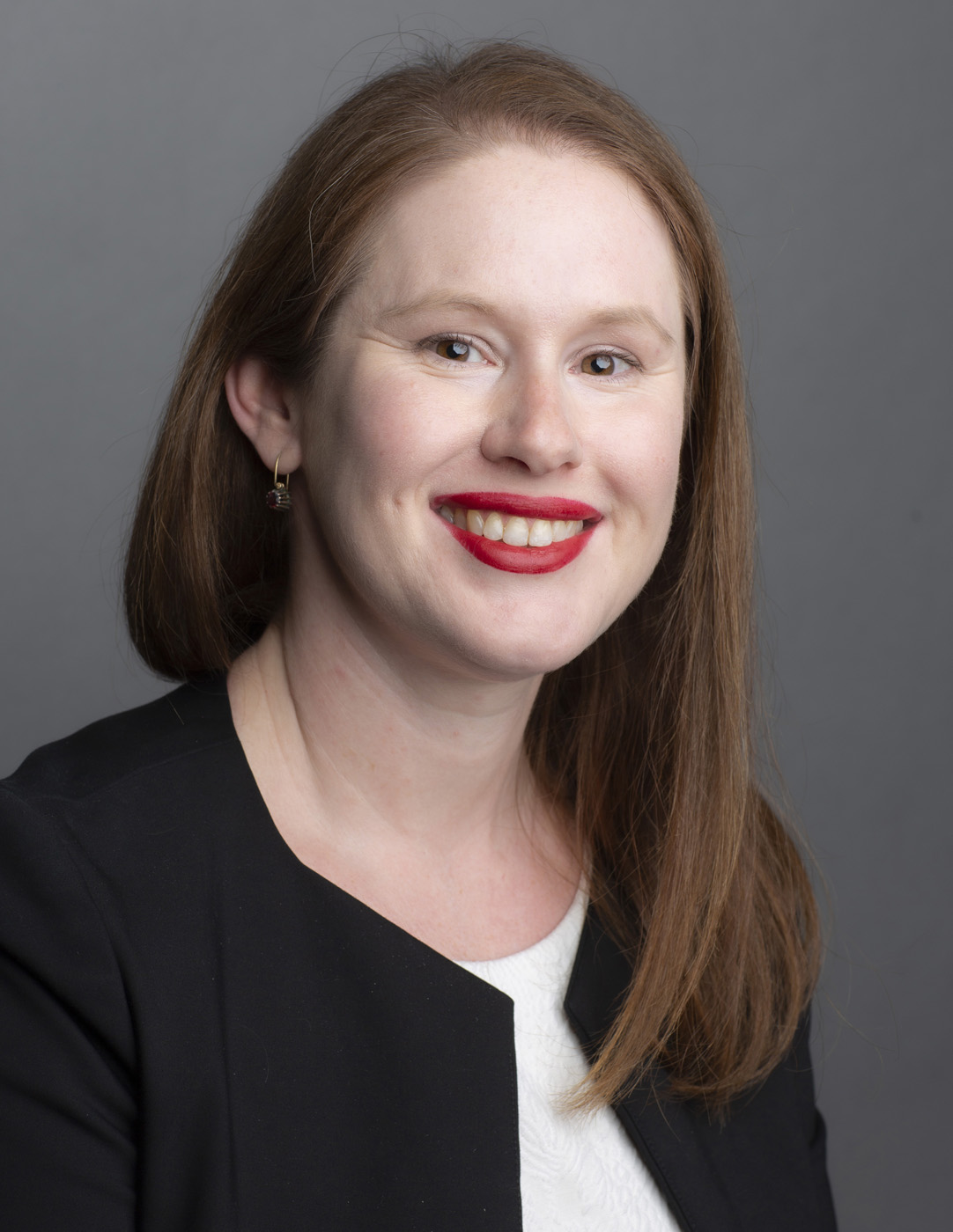 Headshot of woman with shoulder-length red hair looking at camera and smiling