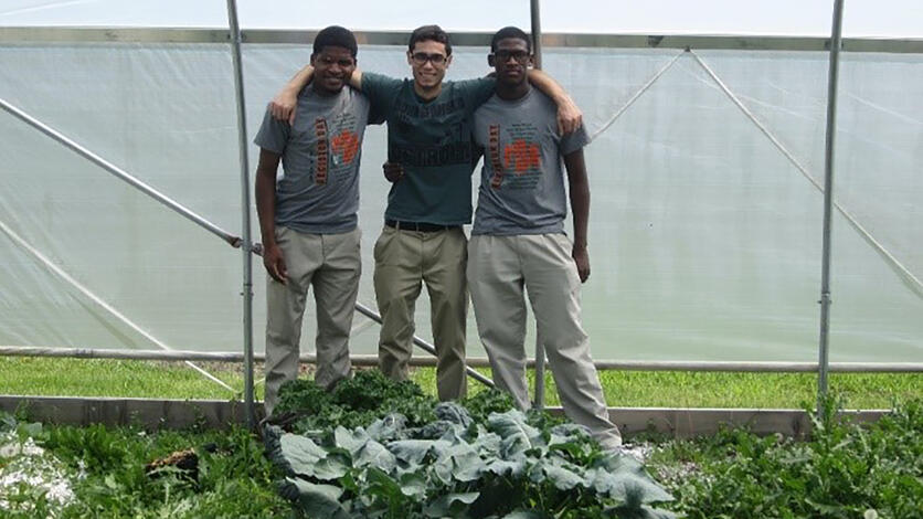 Students pose for a photo inside the learning garden's greenhouse.