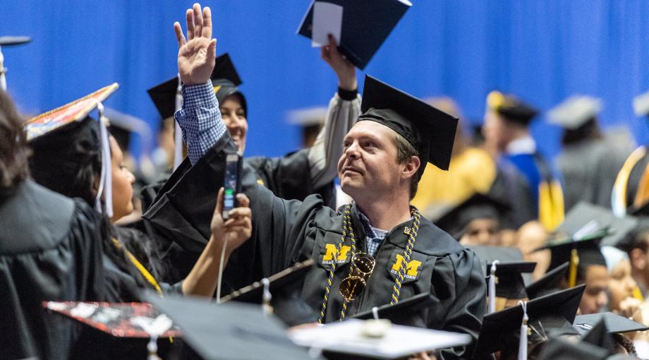 male graduate waving