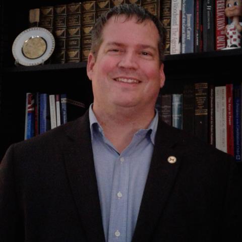 Mitchel Sollenberger smiling in dark blazer and light blue shirt