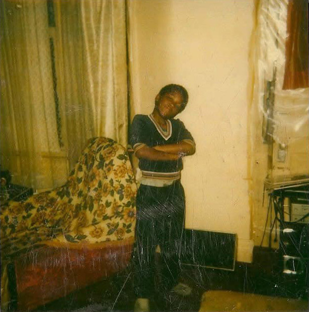 A young African American boy stands for a portrait with his arms crossed in his 1970s childhood home 