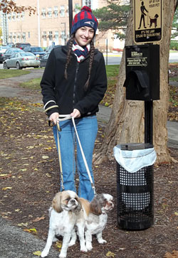 Woman with 2 dogs stands next to new pet waste disposal station