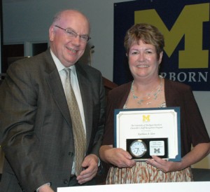 Kathleen Herr holding a certificate standing next to the Chancellor