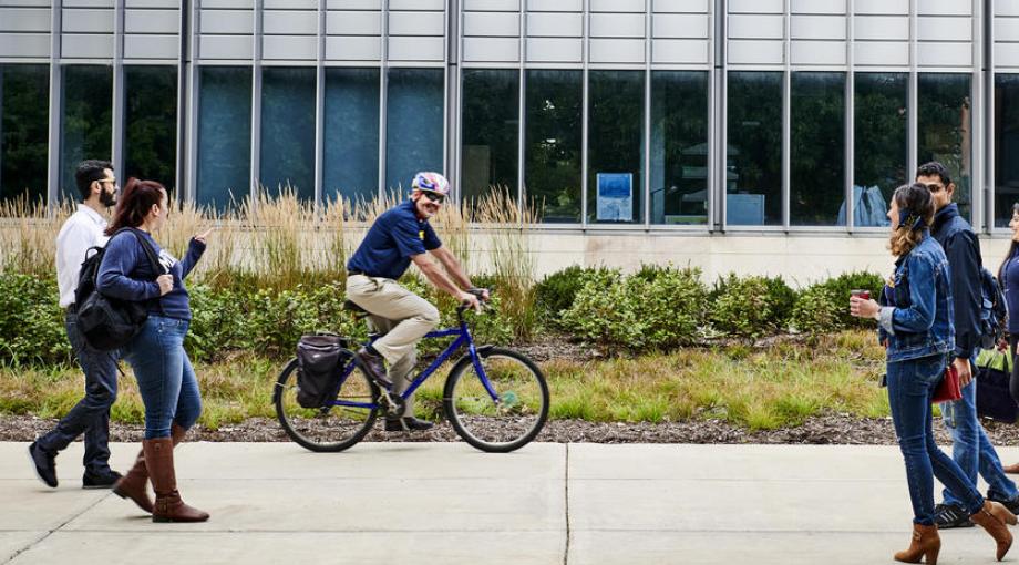   Chancellor Domenico Grasso riding his bicycle across campus.