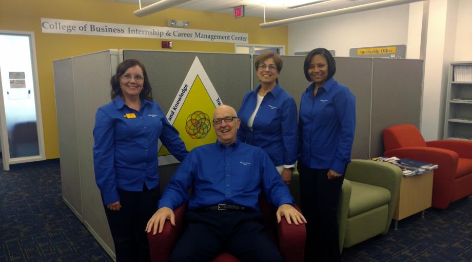 4 staff posing for photograph wearing blue shirts