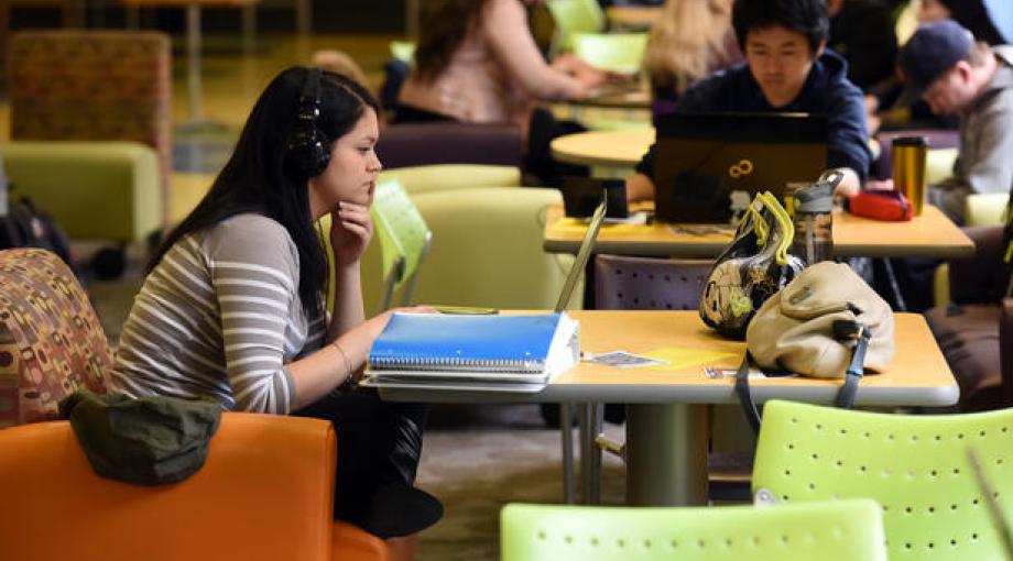 Student studying at a table with her laptop wearing headphones.