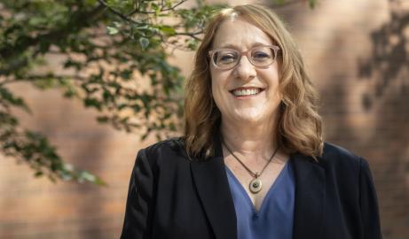 Woman with glasses, standing near tree, smiling