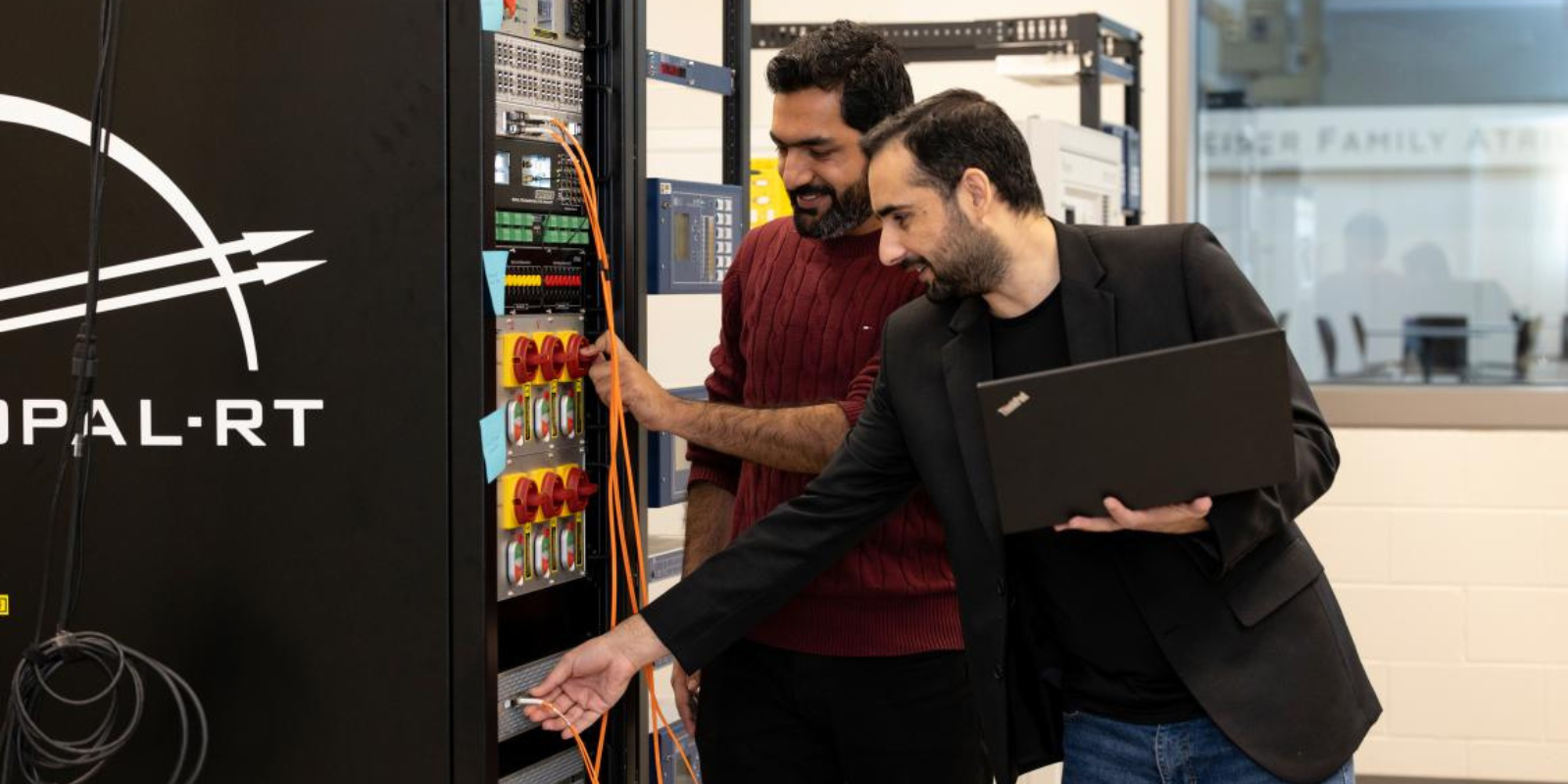 Doctoral students Ali Hassan (left) and Shahid Aziz Khan work with an OPAL-RT "hardware-in-the-loop" simulator in the lab of Electrical and Computer Engineering Professor Wencong Su.