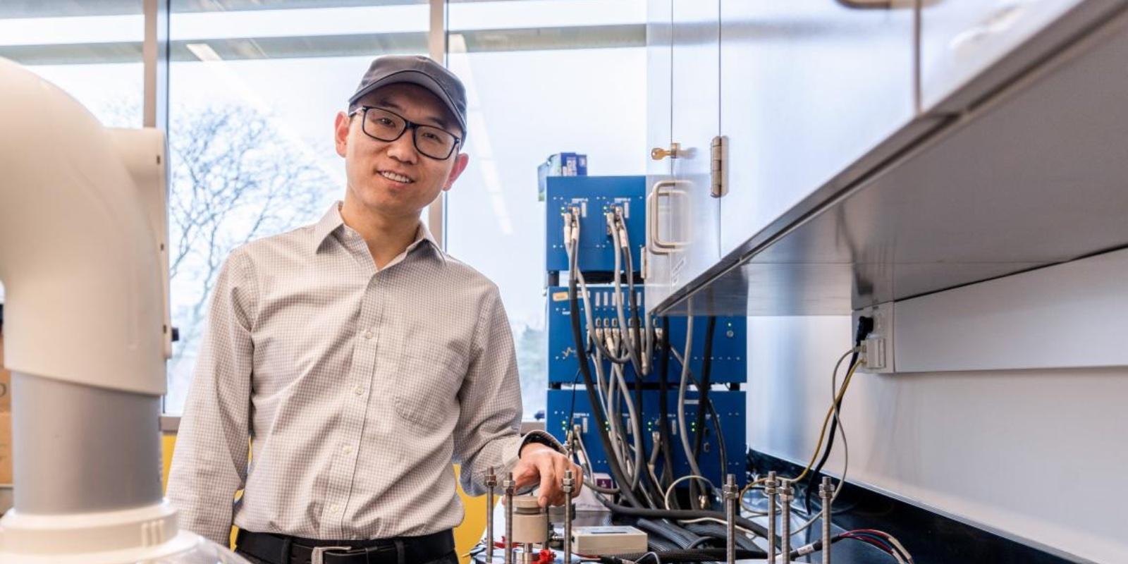 Surrounded by lab equipment, Associate Professor Xuan Zhou poses for a portrait in his UM-Dearborn battery lab