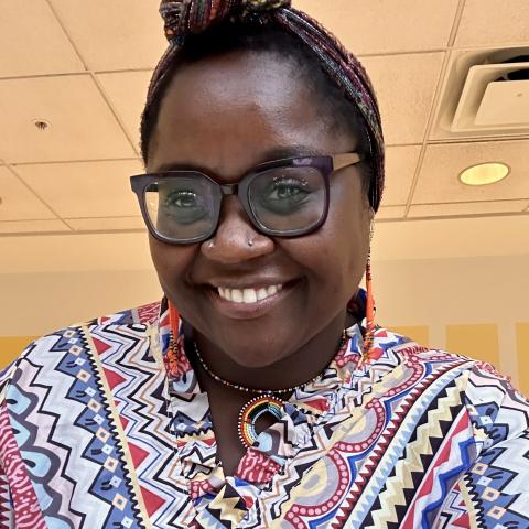 Image of woman, smiling, wearing a striped dress and headwrap