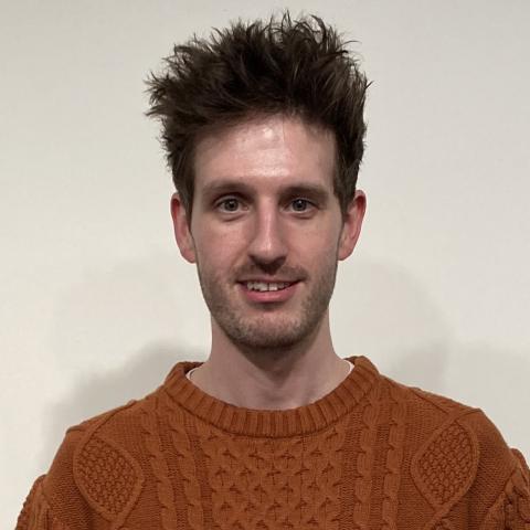 Headshot image of man in brown sweater facing the camera