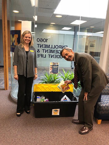 September 19, 2018: Chancellor Grasso makes a donation to the UM-Dearborn Food Pantry. Also pictured, UM-Dearborn dean of students, Amy Finley. 